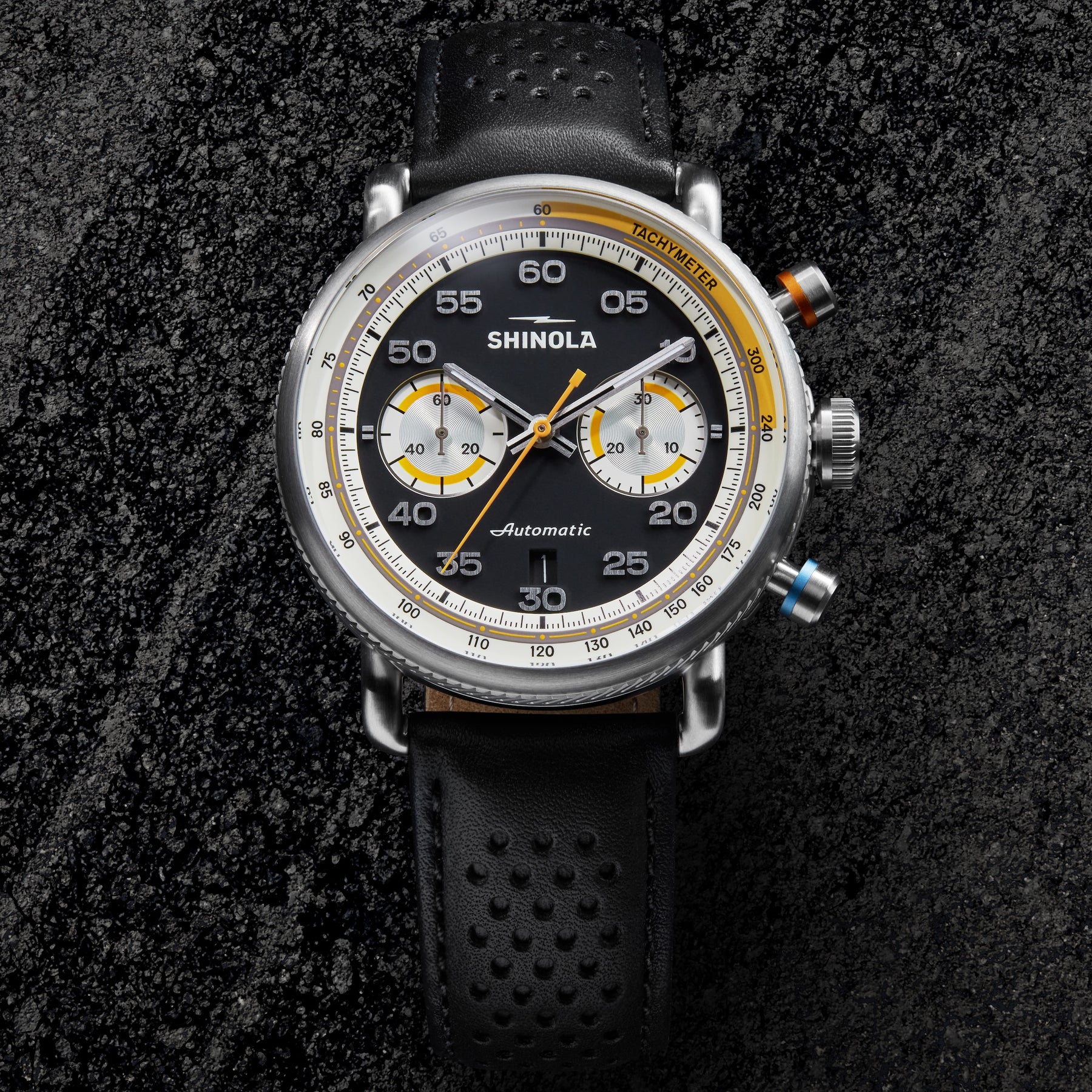 Shinola watch with black strap and detailed face on a dark textured background